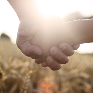 Mutter und Tochter halten sich die Hände im Gegenlicht